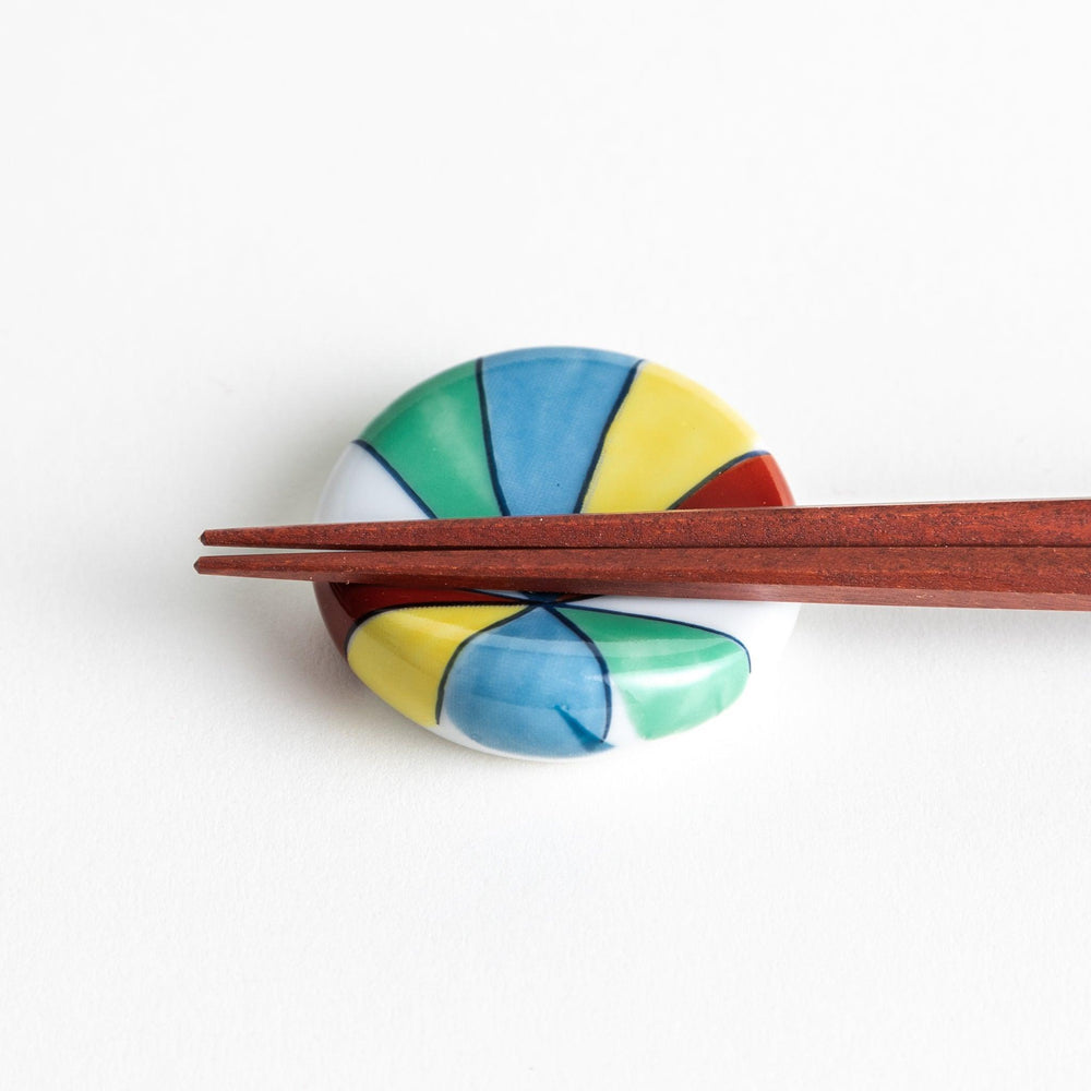 A colorful round ceramic chopstick rest with a pinwheel design.