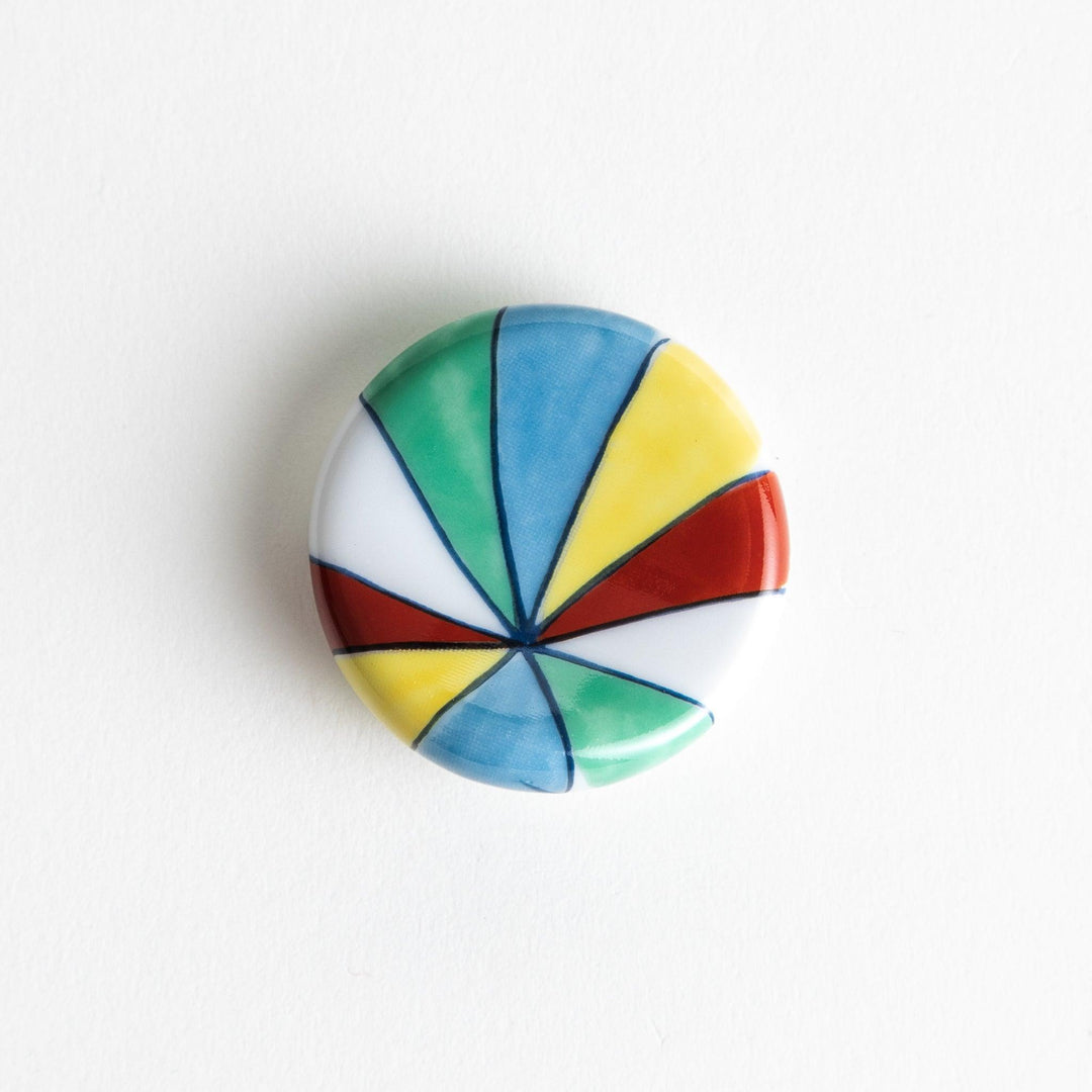 A colorful round ceramic chopstick rest with a pinwheel design.