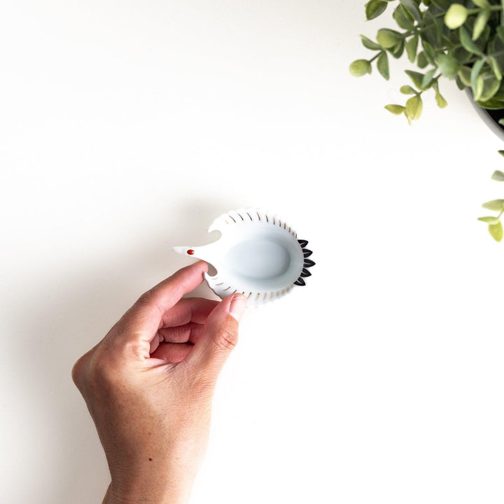 A white, crane-shaped ceramic dish with fine detailing and a small red accent.