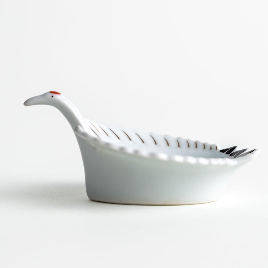 A white, crane-shaped ceramic dish with fine detailing and a small red accent.