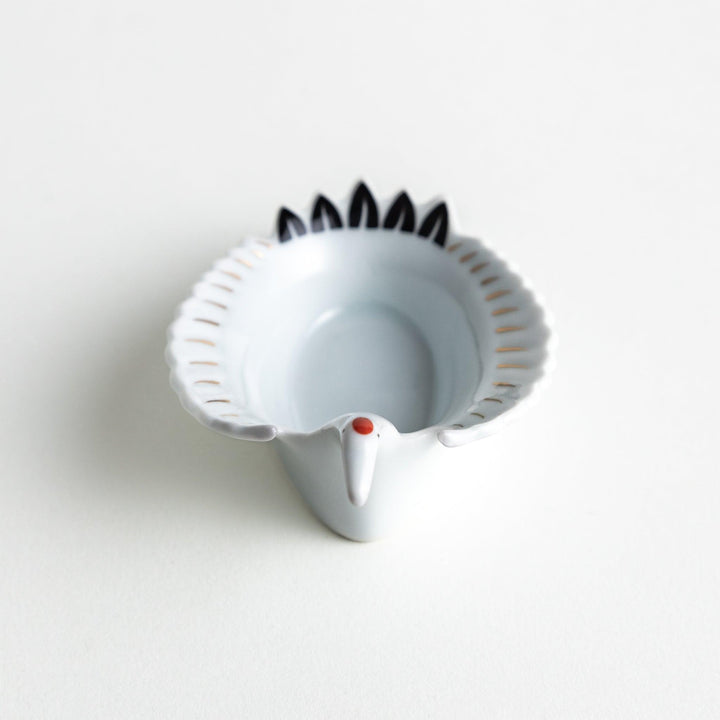 A white, crane-shaped ceramic dish with fine detailing and a small red accent.