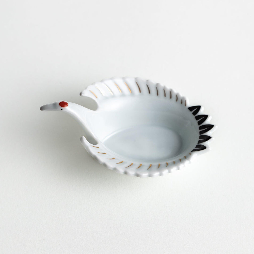 A white, crane-shaped ceramic dish with fine detailing and a small red accent.