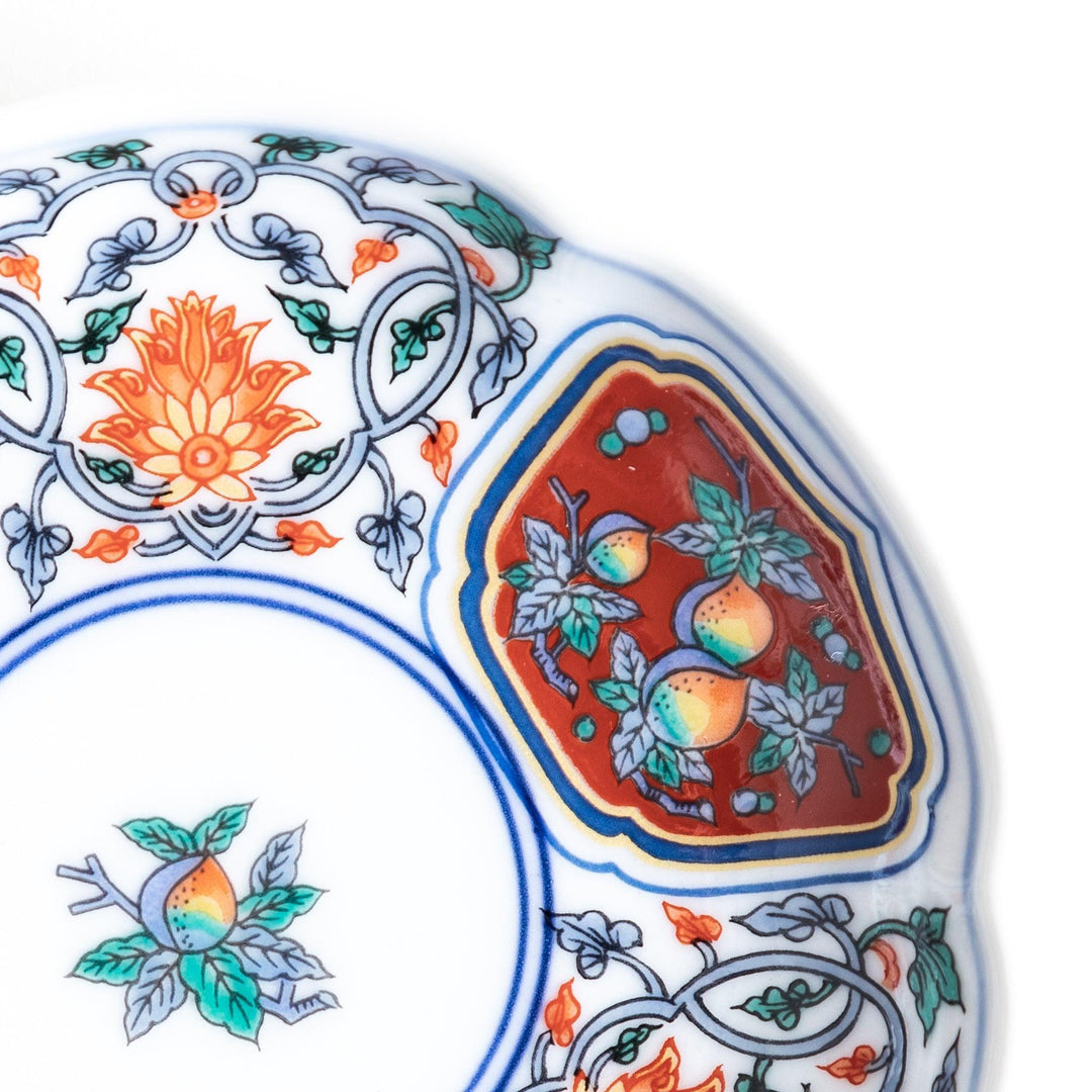 A round sauce dish with a central floral motif, surrounded by red and green floral patterns on the rim with blue accents.