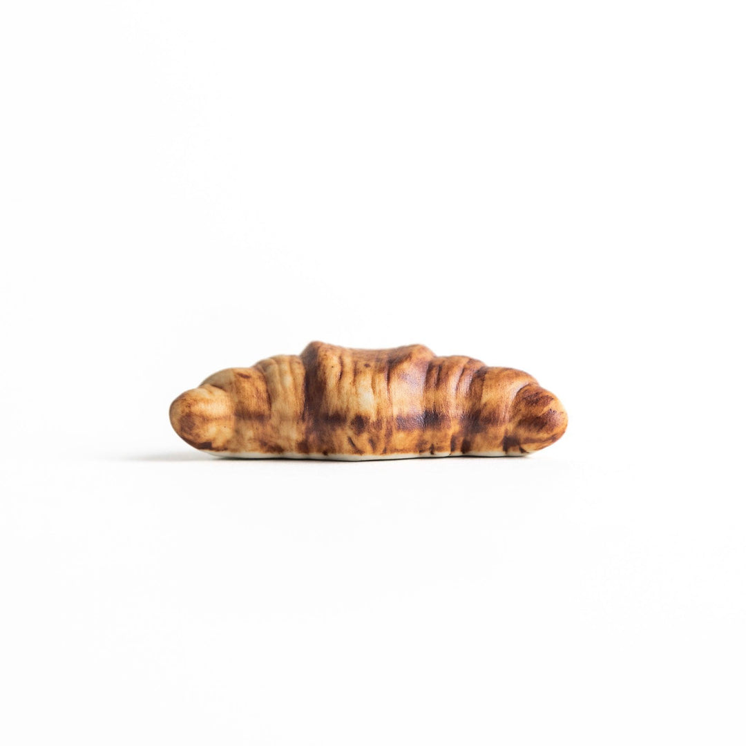 A ceramic chopstick rest designed to resemble a miniature croissant.