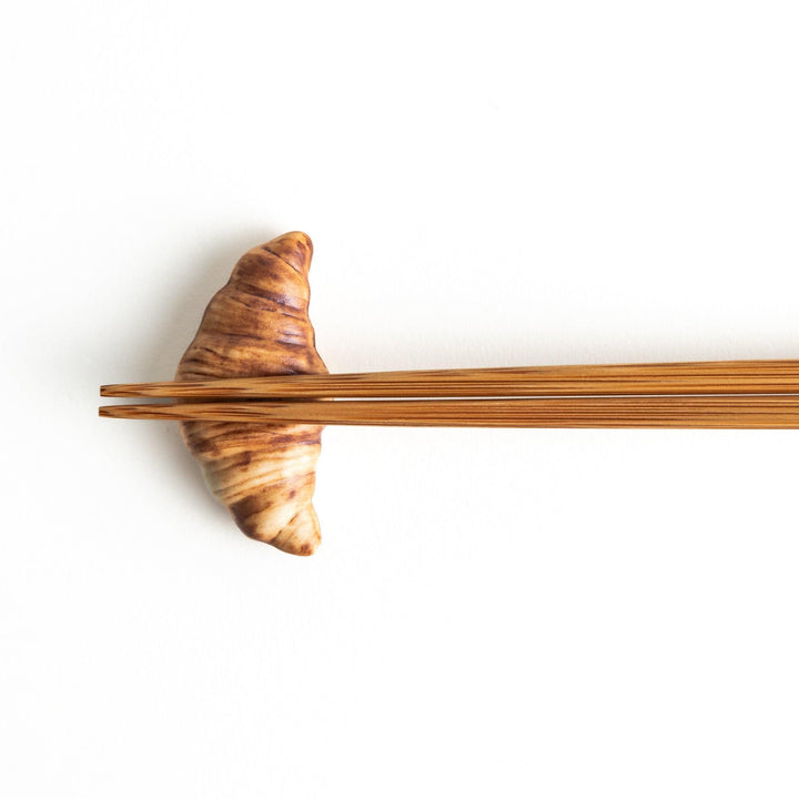 A ceramic chopstick rest designed to resemble a miniature croissant.