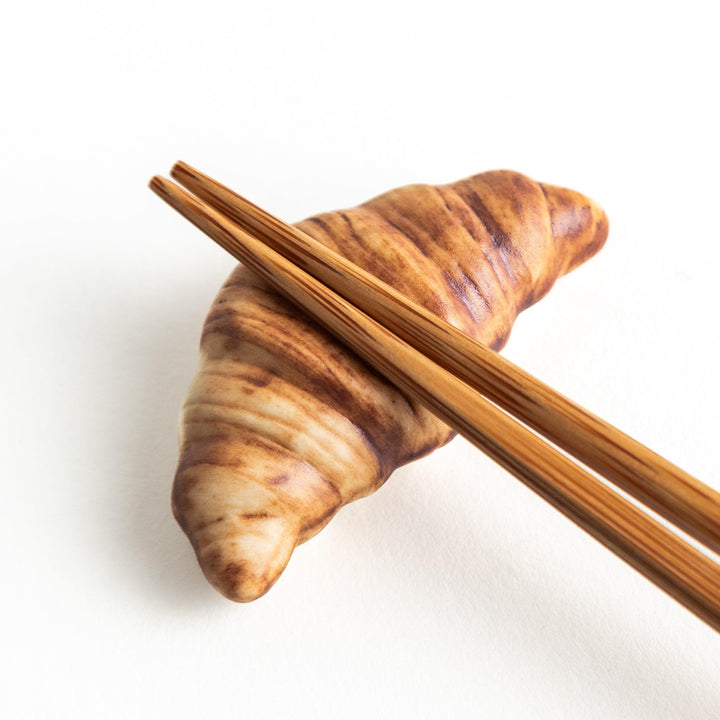 A ceramic chopstick rest designed to resemble a miniature croissant.