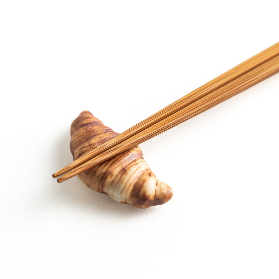 A ceramic chopstick rest designed to resemble a miniature croissant.