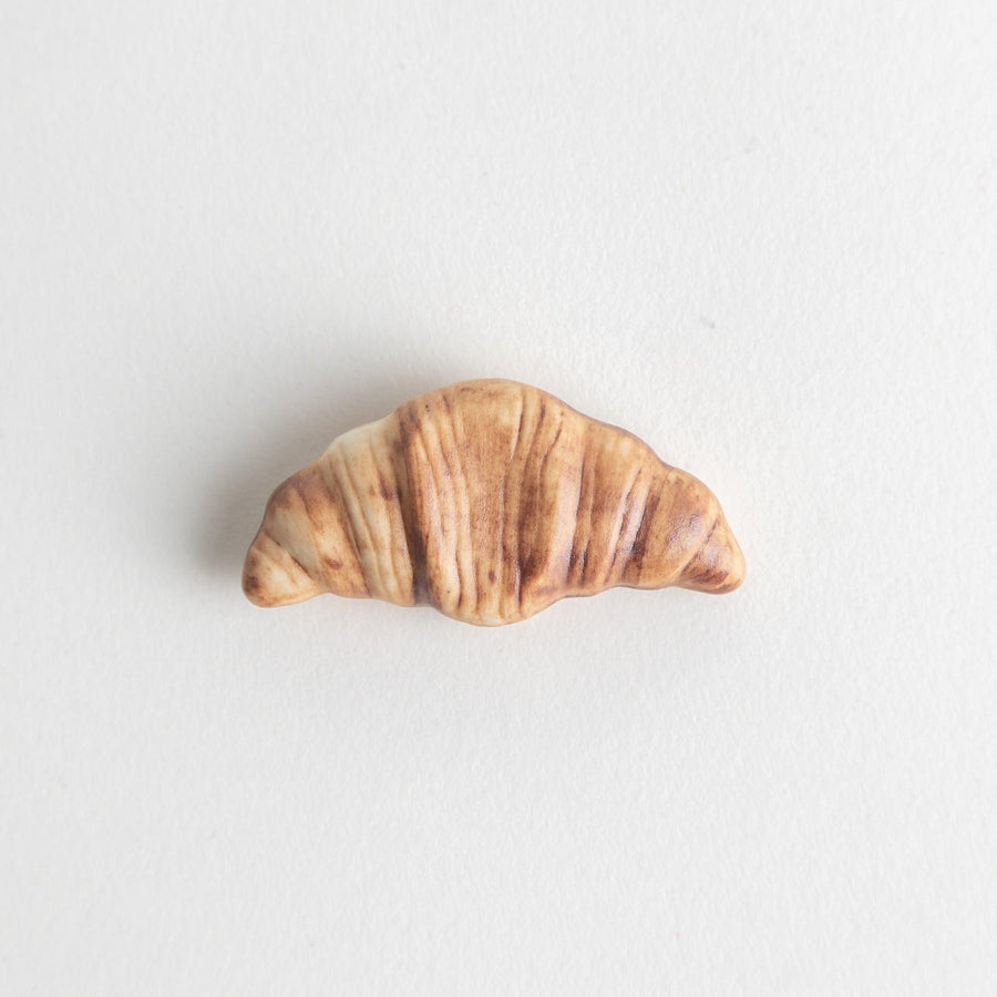 A ceramic chopstick rest designed to resemble a miniature croissant.