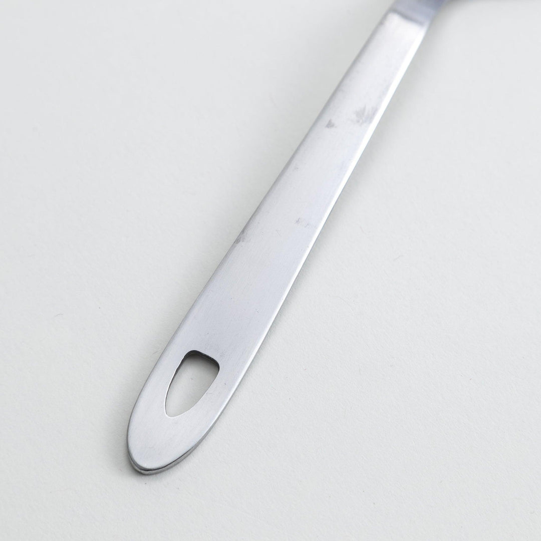 A stainless steel serving spoon with a smooth, polished finish and a slight serrated edge, ideal for cutting and serving.