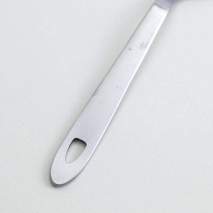 A stainless steel serving spoon with a smooth, polished finish and a slight serrated edge, ideal for cutting and serving.