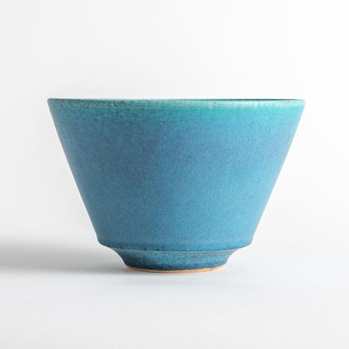 A bowl with a matte turquoise glaze, featuring a minimalist design.