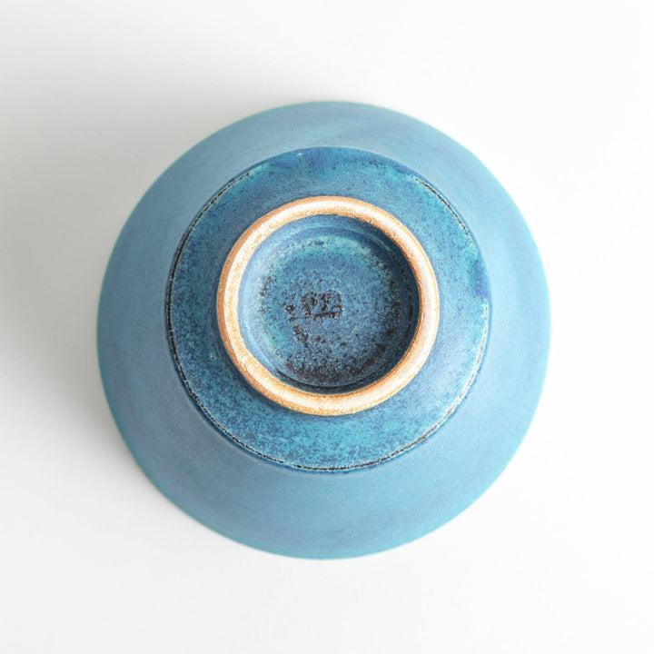 A bowl with a matte turquoise glaze, featuring a minimalist design.