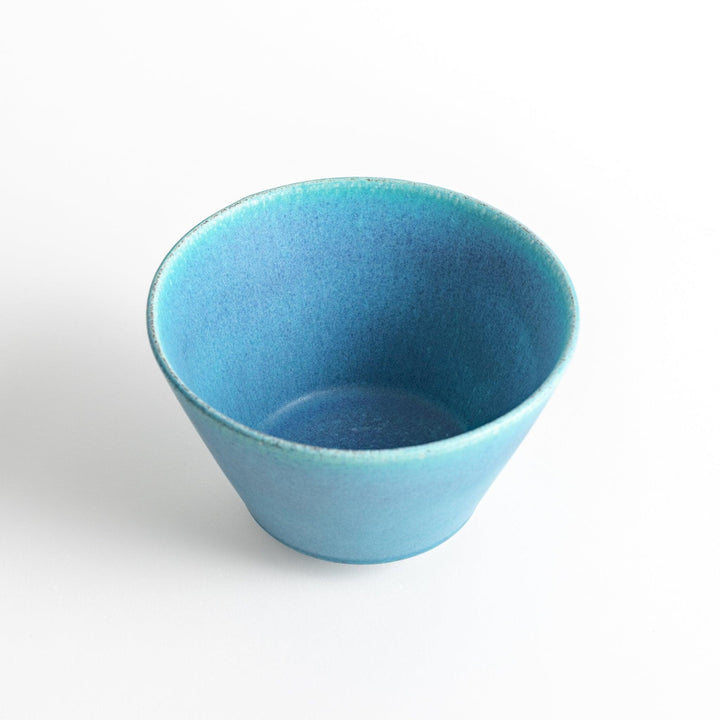 A bowl with a matte turquoise glaze, featuring a minimalist design.