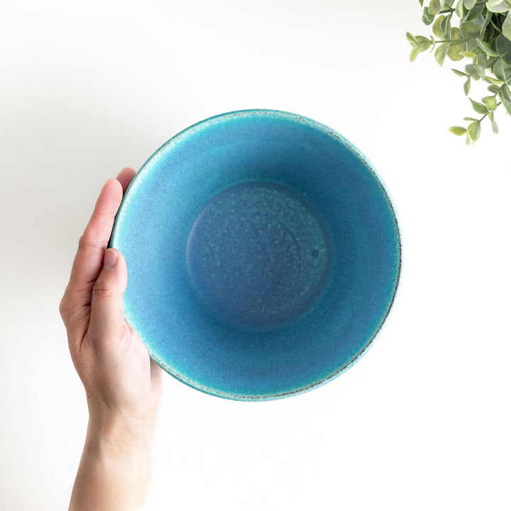 A bowl with a matte turquoise glaze, featuring a minimalist design.