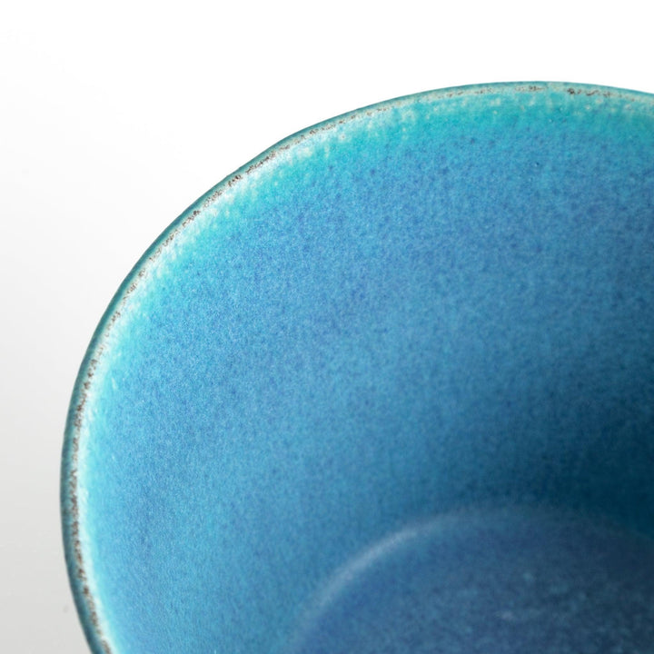 A bowl with a matte turquoise glaze, featuring a minimalist design.