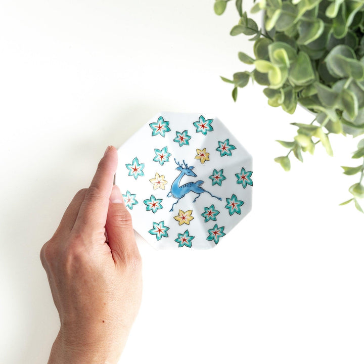 Octagonal plate with a blue deer surrounded by red and green floral patterns.
