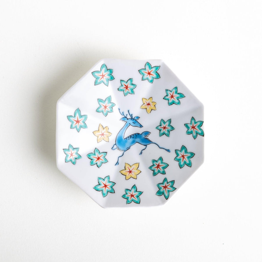 Octagonal plate with a blue deer surrounded by red and green floral patterns.
