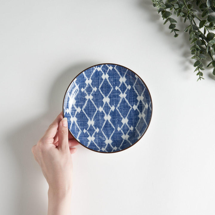 A round dessert plate featuring a bold blue and white lattice pattern.