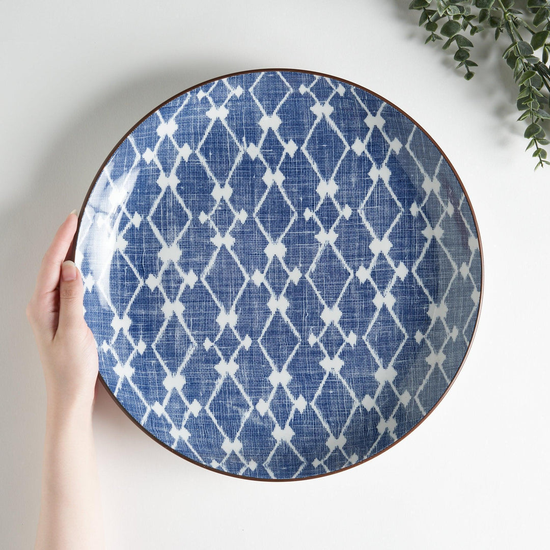 A round serving plate featuring a bold blue and white geometric lattice pattern, perfect for a contemporary table setting.