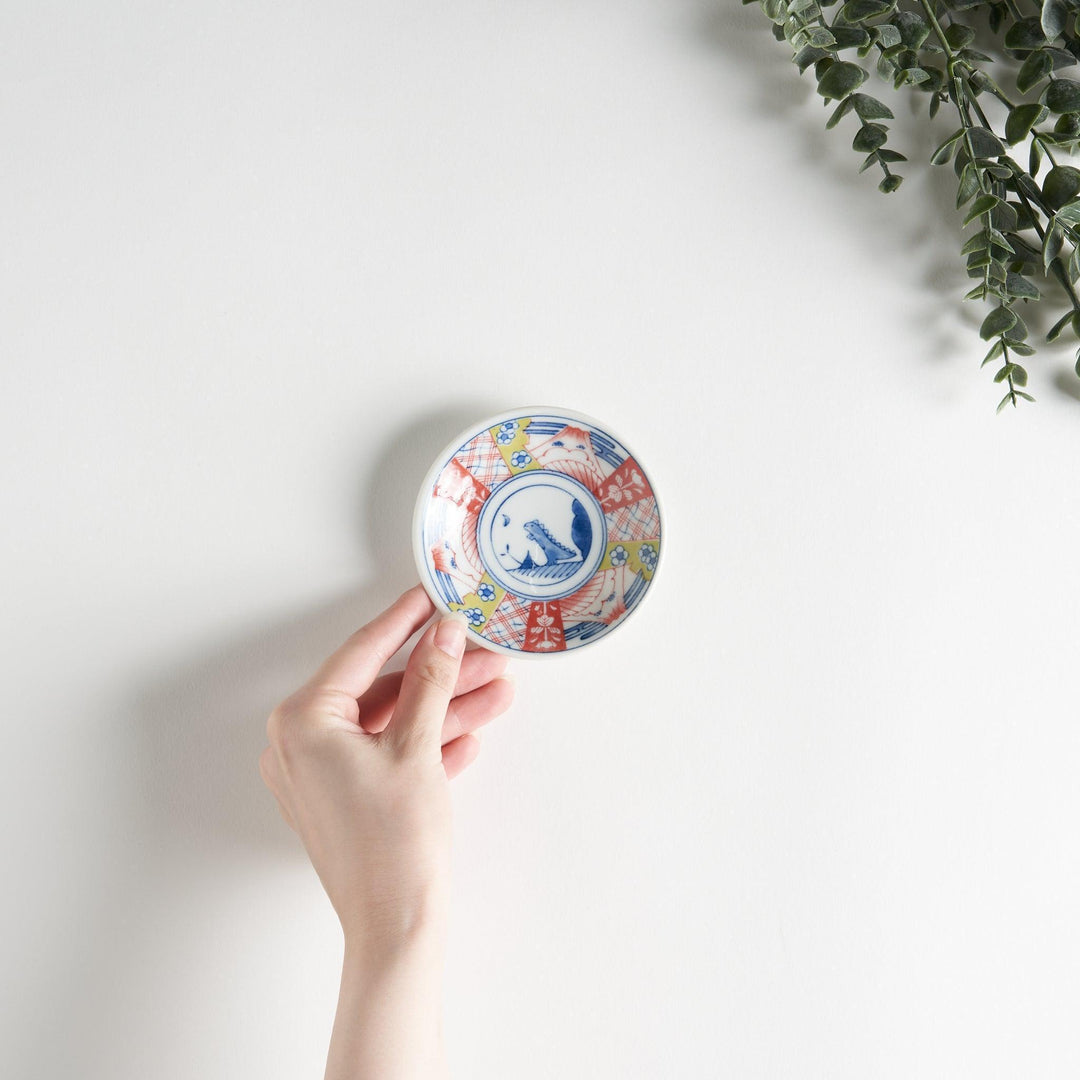 A set of four small, decorative porcelain plates in a gift box, each plate featuring a different dinosaur design in blue and red.