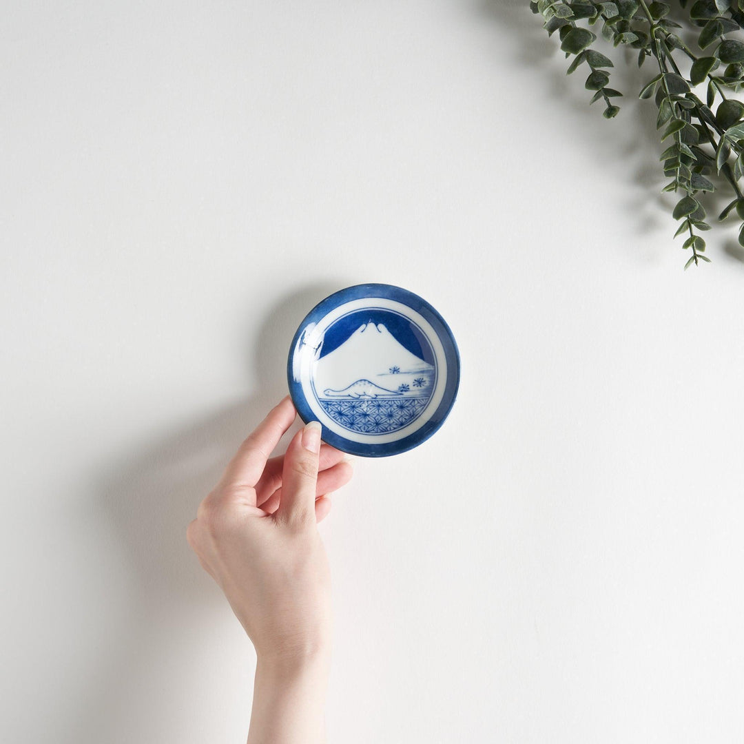 A set of four small, decorative porcelain plates in a gift box, each plate featuring a different dinosaur design in blue and red.