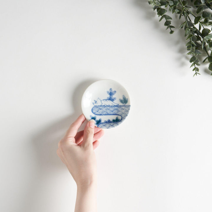 A set of four small, decorative porcelain plates in a gift box, each plate featuring a different dinosaur design in blue and red.