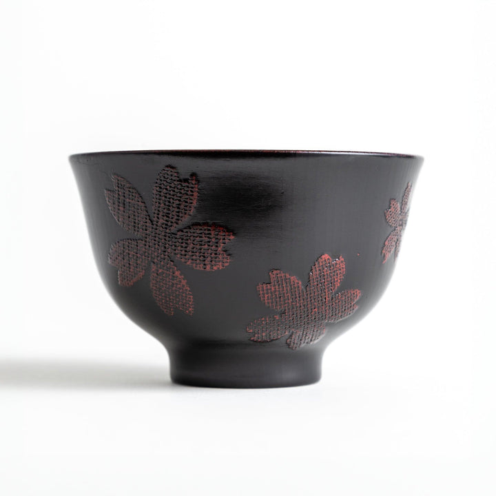 A lacquered bowl featuring a textured black floral design and a smooth, polished finish. Available in black or red.