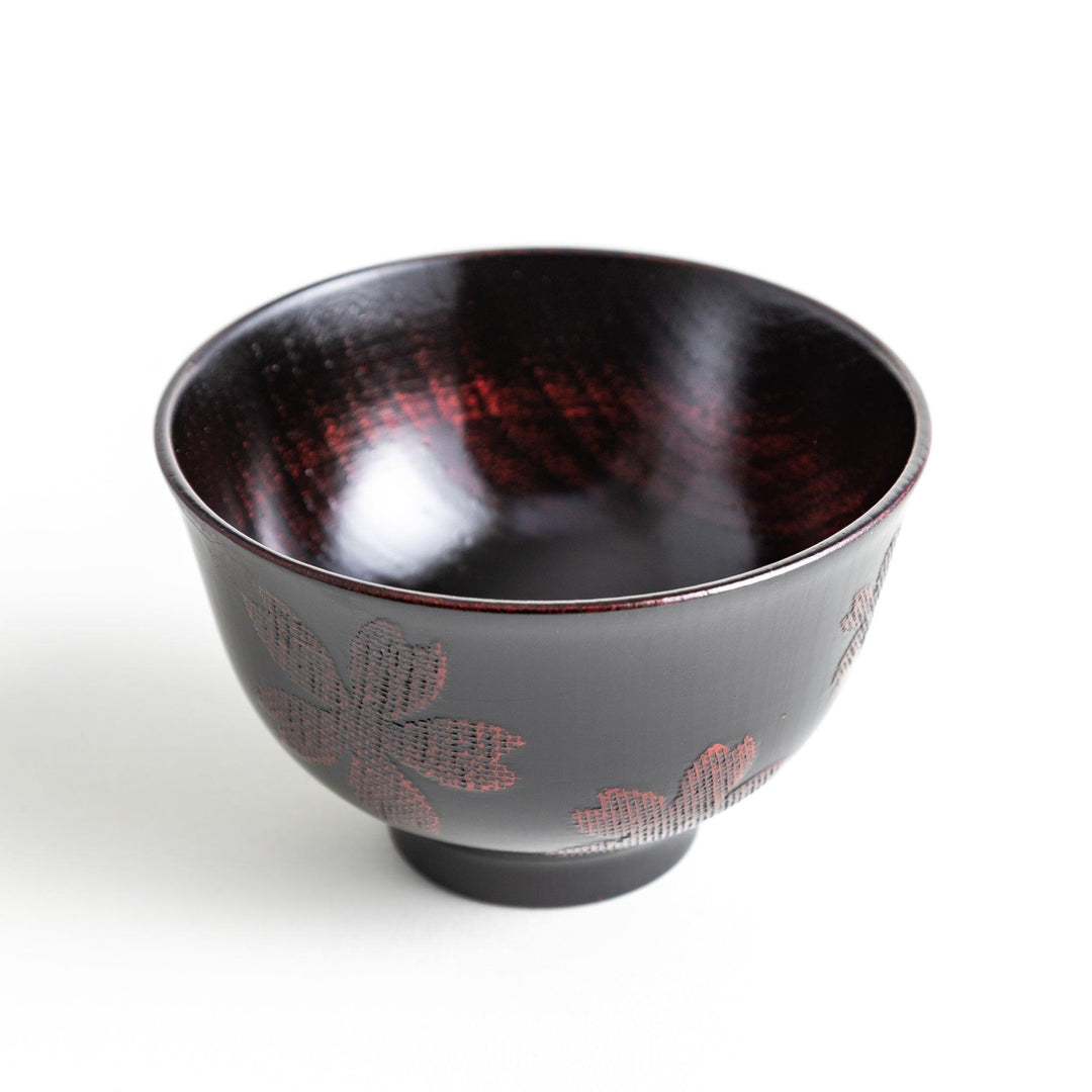 A lacquered bowl featuring a textured black floral design and a smooth, polished finish. Available in black or red.