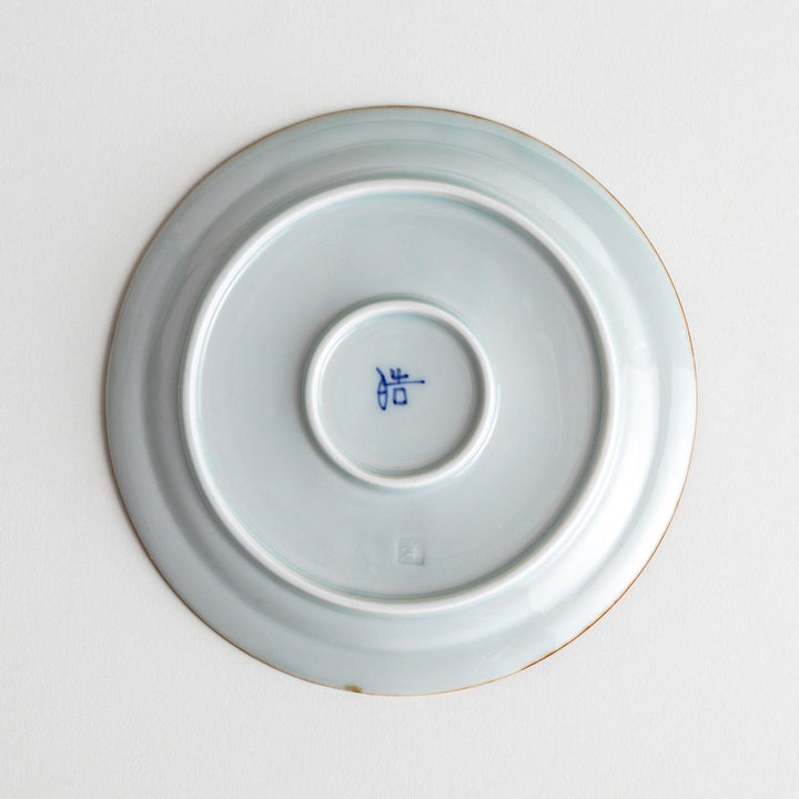 A small porcelain dessert plate with a scalloped edge, decorated with blue and white floral motifs and brown accent trim.