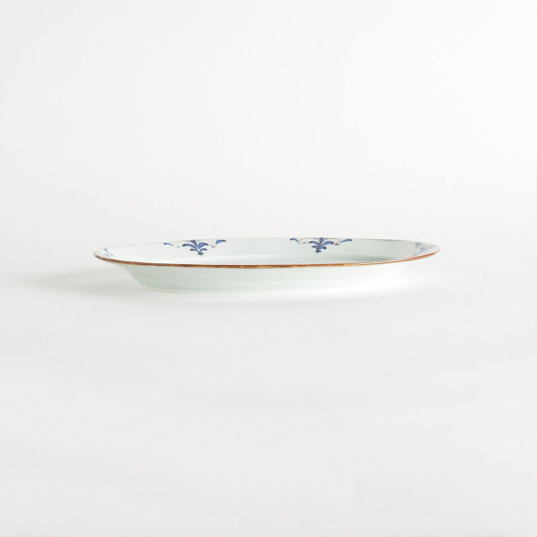 A porcelain oval dinner plate, decorated with blue and white floral motifs with brown accent trim.