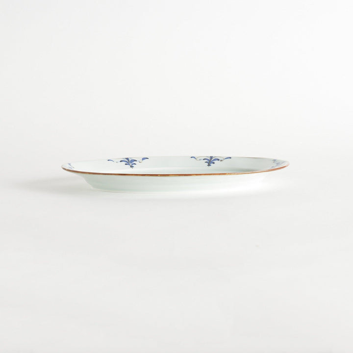 A porcelain oval dinner plate, decorated with blue and white floral motifs with brown accent trim.