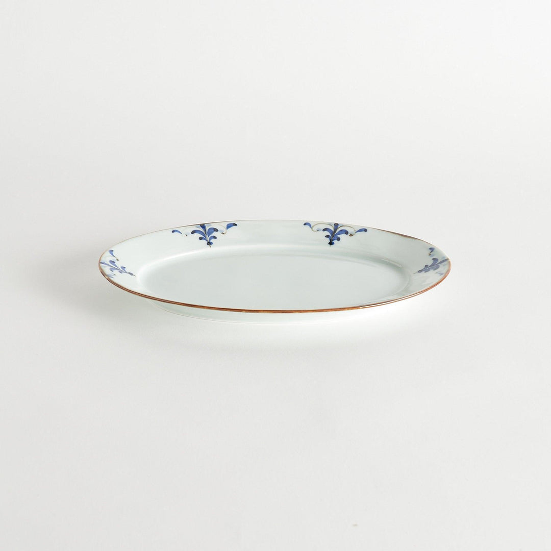 A porcelain oval dinner plate, decorated with blue and white floral motifs with brown accent trim.