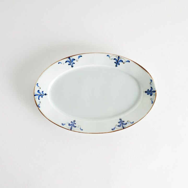 A porcelain oval dinner plate, decorated with blue and white floral motifs with brown accent trim.