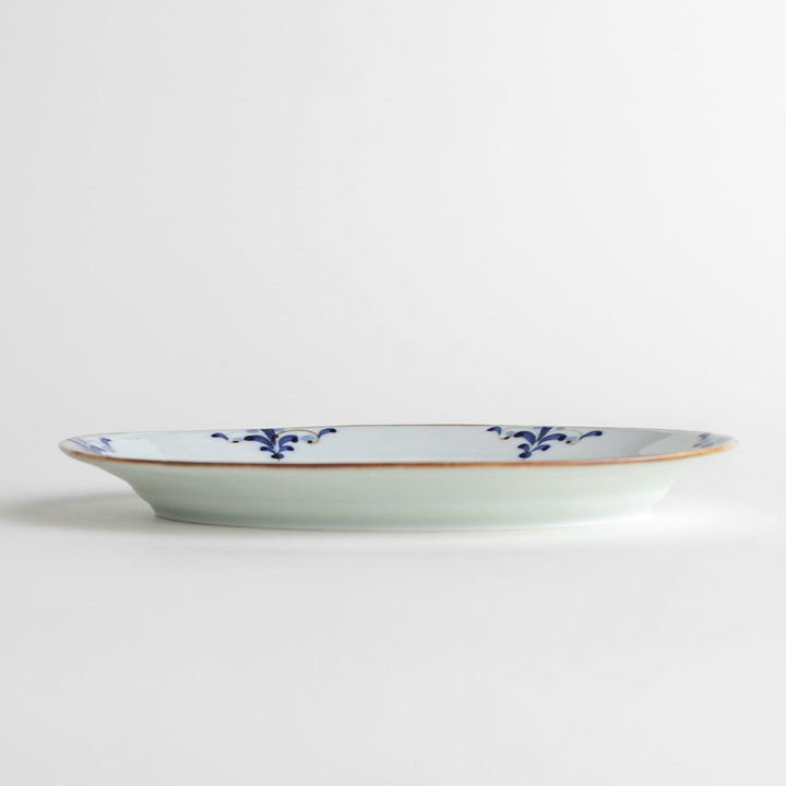 A porcelain oval salad plate, decorated with blue and white floral motifs and brown accent trim.