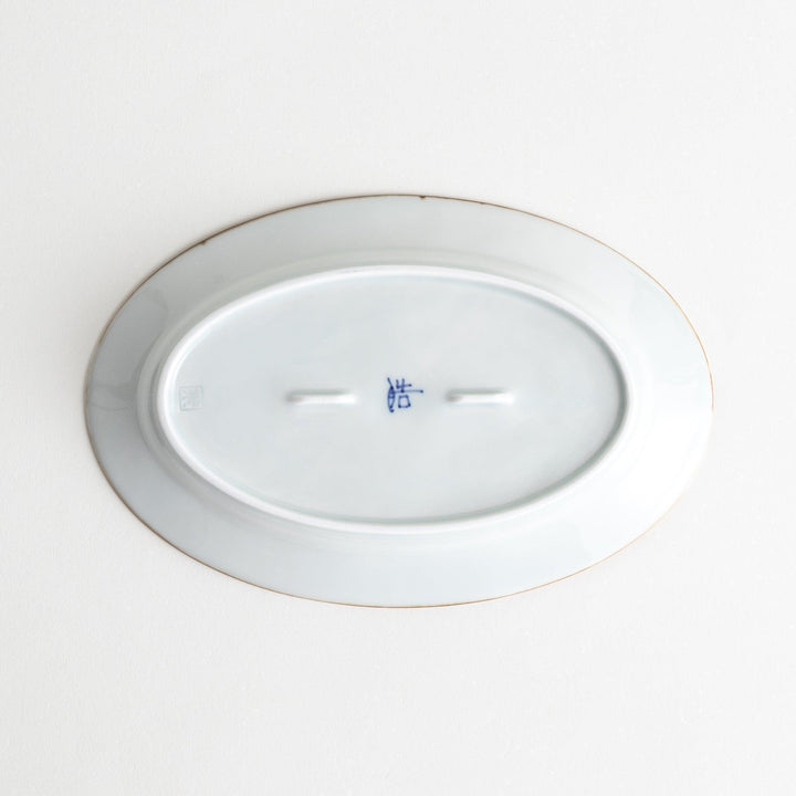 A porcelain oval salad plate, decorated with blue and white floral motifs and brown accent trim.