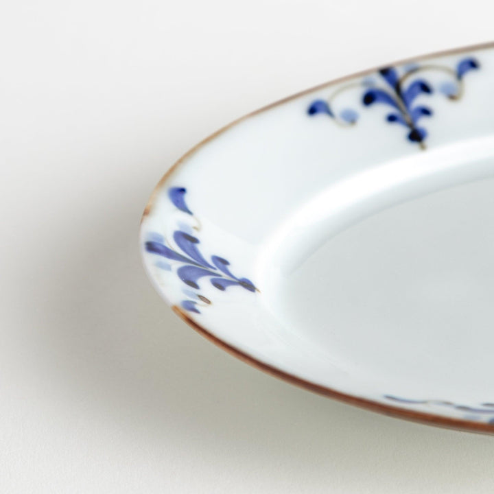 A porcelain oval salad plate, decorated with blue and white floral motifs and brown accent trim.