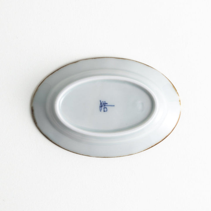 A small porcelain oval sauce dish, decorated with blue and white floral motifs and brown accent trim.