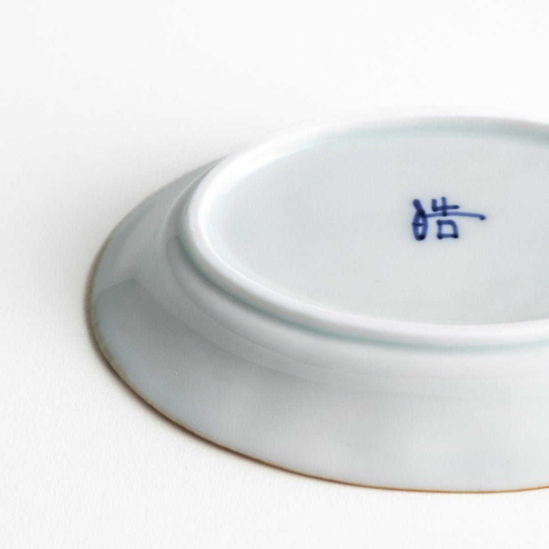 An oval sauce dish featuring blue floral motifs and a ribbed design around the edges with brown accent trim.