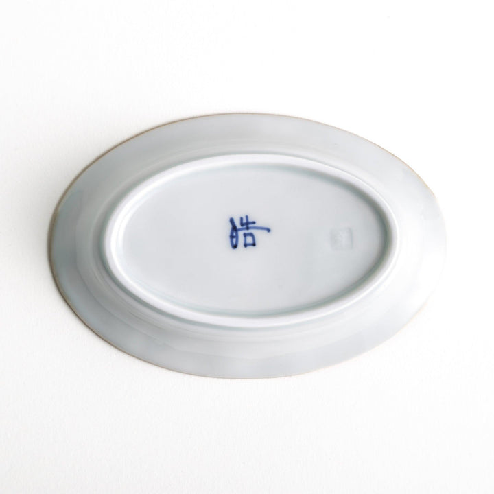 An oval sauce dish featuring blue floral motifs and a ribbed design around the edges with brown accent trim.