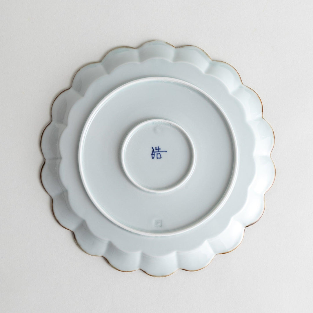 Round white porcelain salad plate with scalloped edges, adorned with a simple blue floral pattern and brown accent trim.