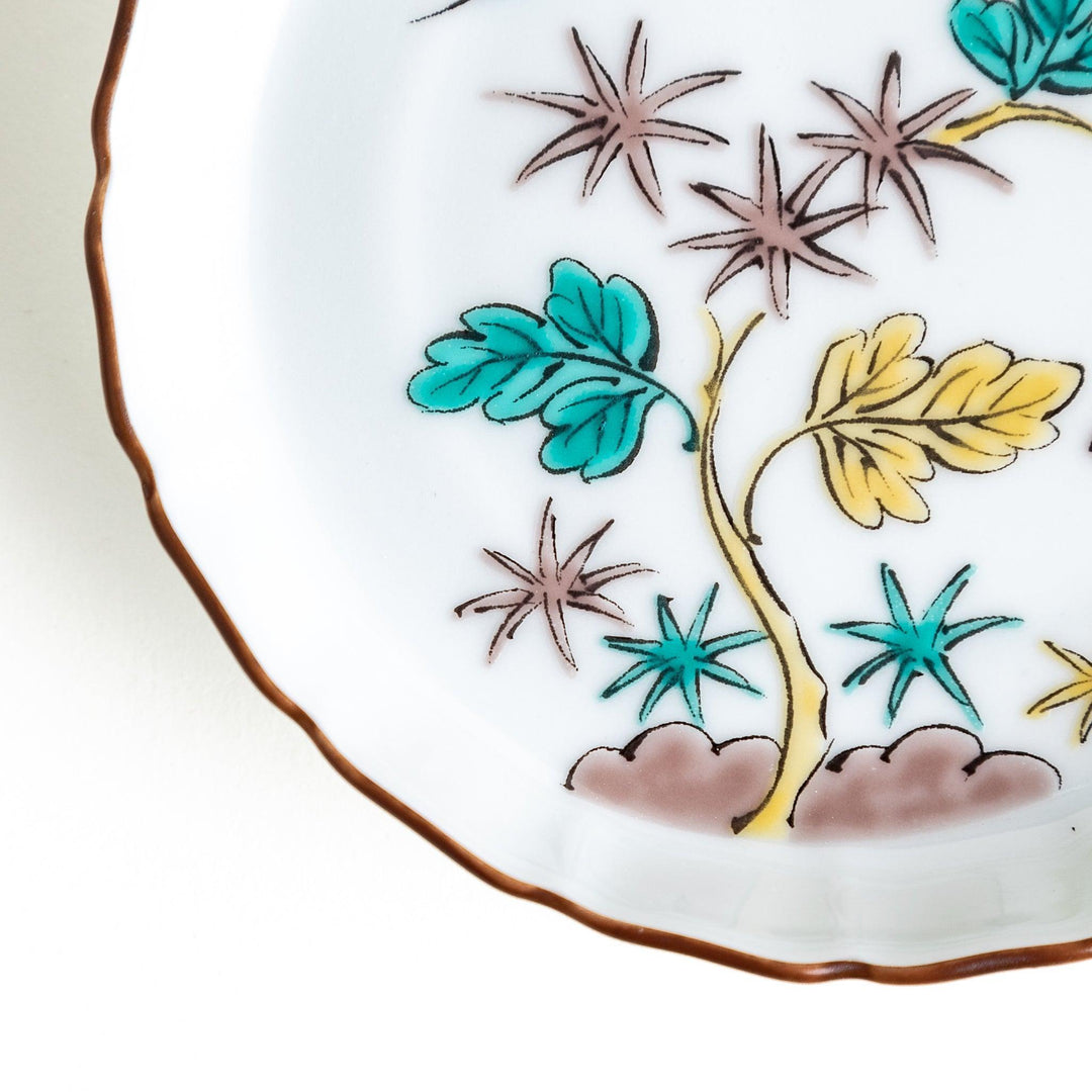 A white ceramic plate with a scalloped edge, decorated with a colorful floral pattern and Mount Fuji in the background.