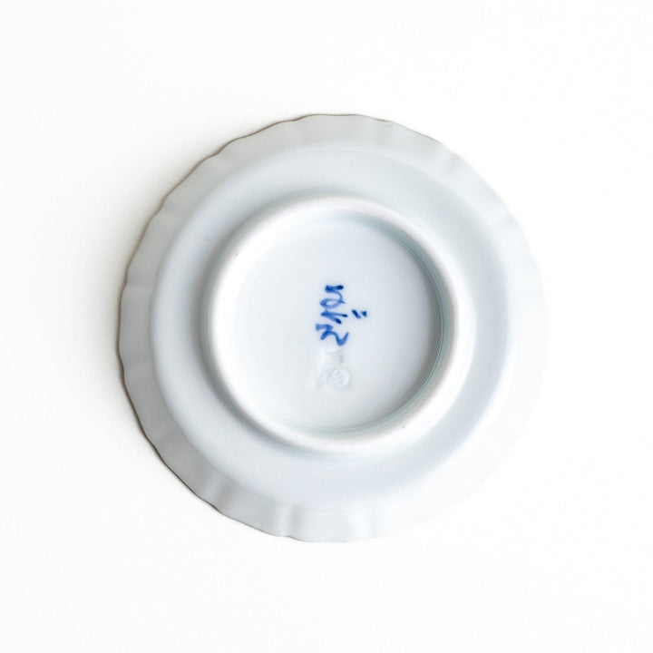 A white ceramic plate with a scalloped edge, decorated with a colorful floral pattern and Mount Fuji in the background.