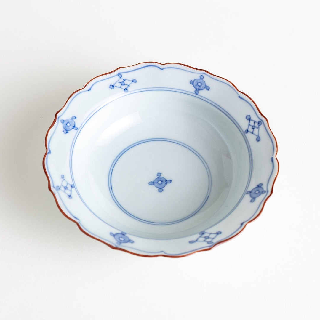 A ceramic bowl featuring a blue geometric motif and scalloped edges.