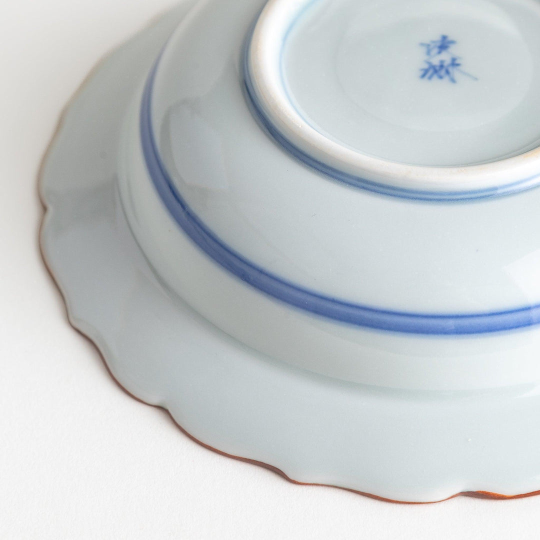 A ceramic bowl featuring a blue geometric motif and scalloped edges.