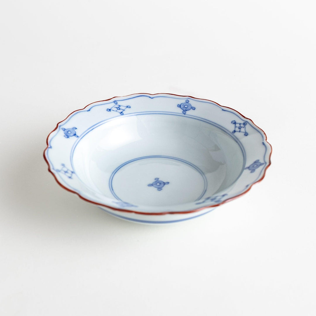 A ceramic bowl featuring a blue geometric motif and scalloped edges.