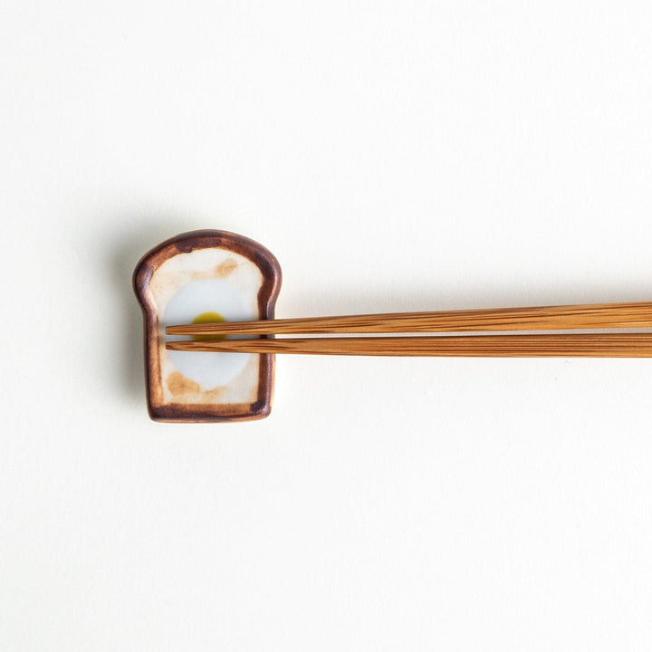 A ceramic chopstick rest resembling a fried egg on toast.