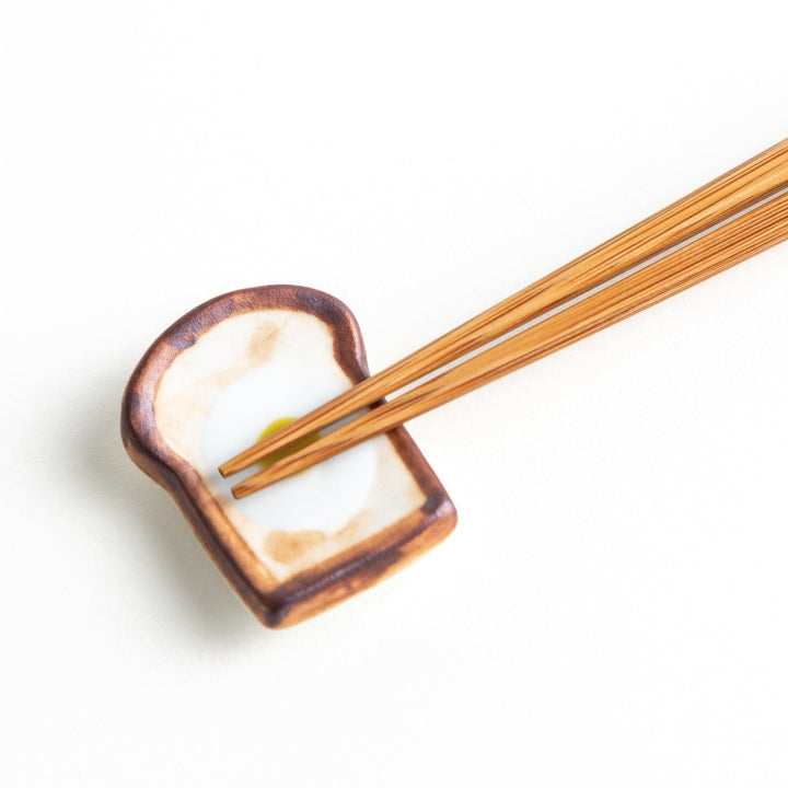 A ceramic chopstick rest resembling a fried egg on toast.