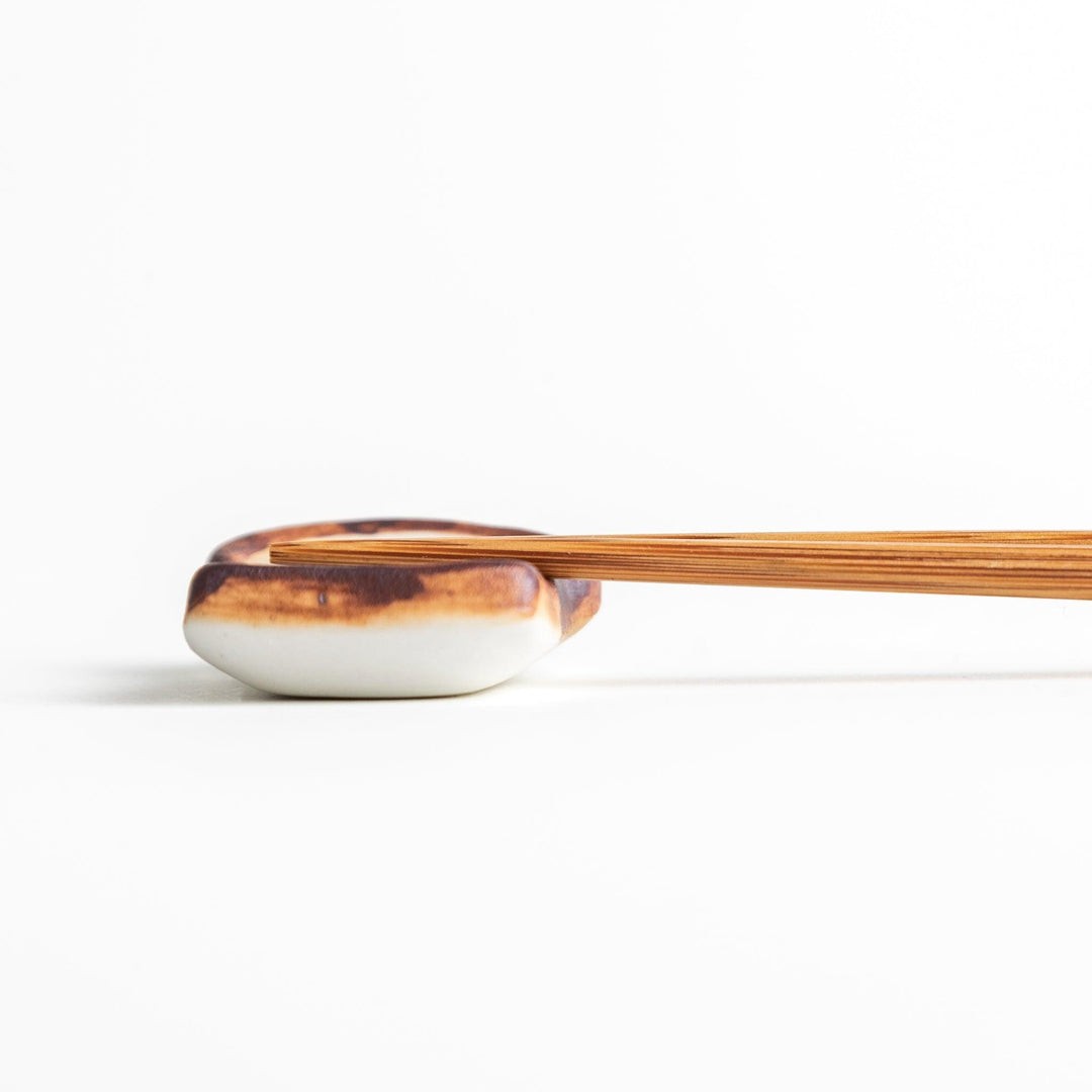 A ceramic chopstick rest resembling a fried egg on toast.