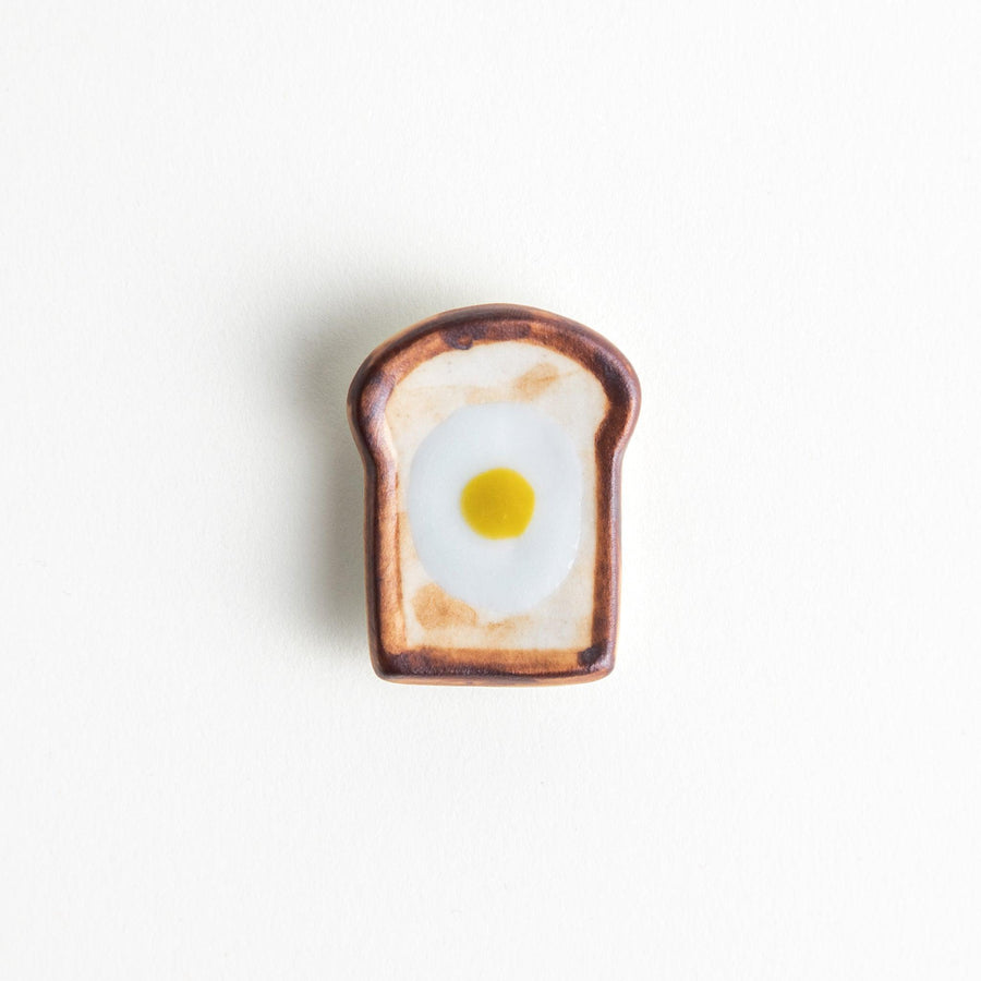 A ceramic chopstick rest resembling a fried egg on toast.