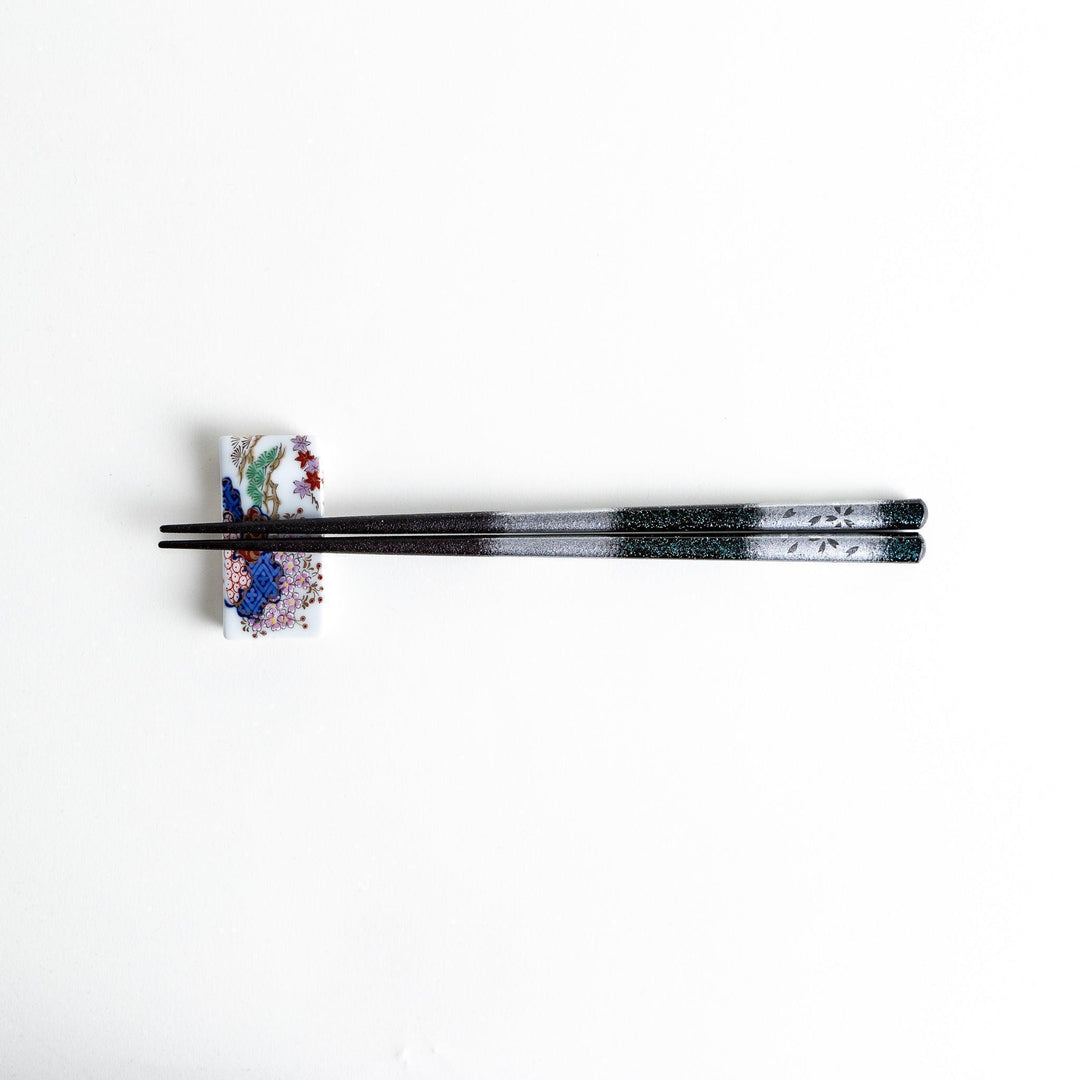 A pair of chopsticks with a gold and silver gradient design.